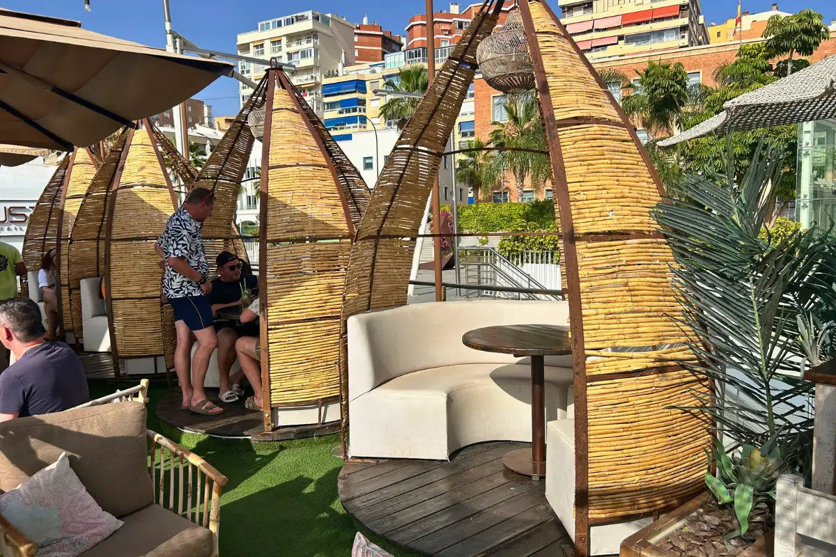 Bamboo cabanas and table seating with harbour views on the terrace at Nusa, Malaga