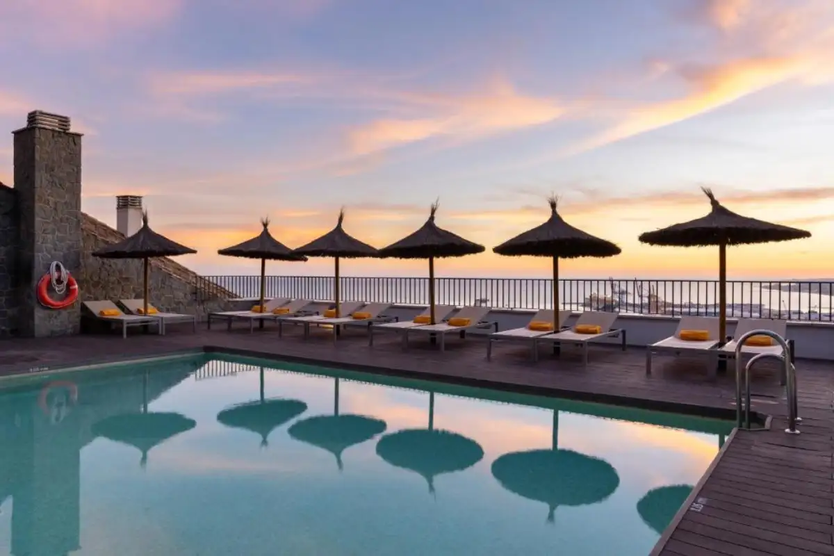 Pool with thatched parasols and loungers at sunset at Parador de Malaga Gibralfaro
