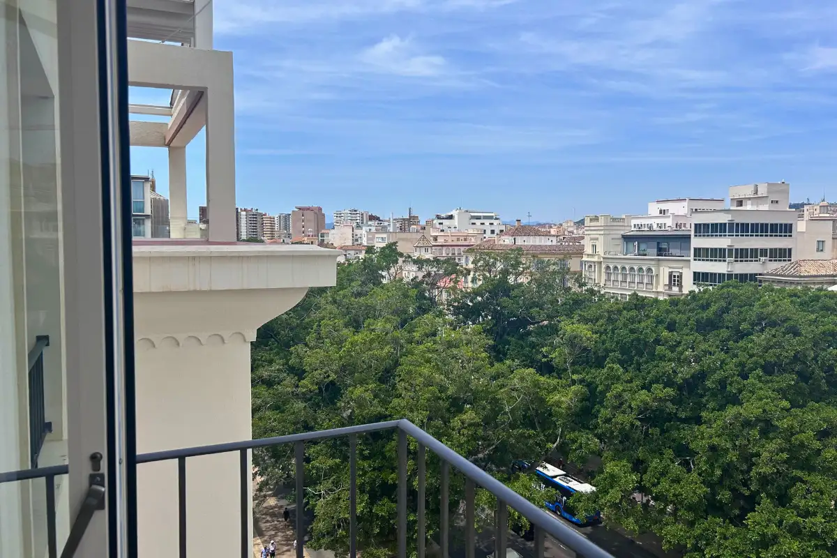 Balcony view over leafy park gardens and the city at SOHO Boutique Equitativa, Malaga