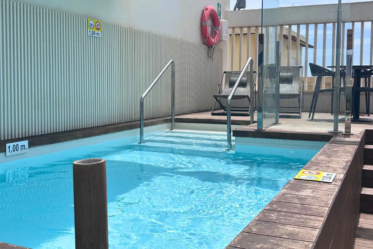 Compact rooftop plunge pool with steps and wooden deck at SOHO Boutique Equitativa, Malaga