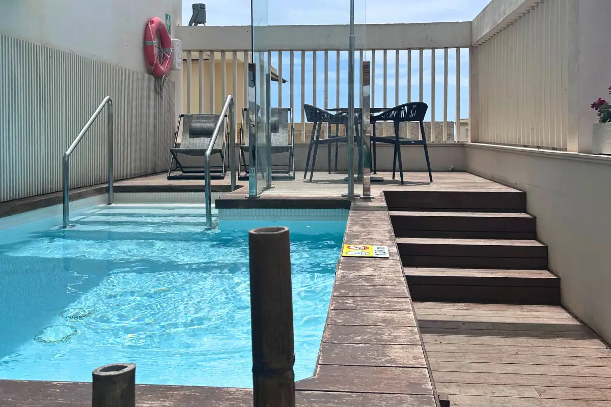Decked rooftop pool terrace with steps and high tables at Soho Boutique Equitativa in Malaga