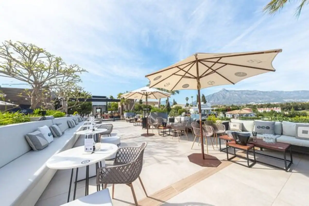Sunny dining terrace with parasols and mountain views at Air by Breathe Marbella