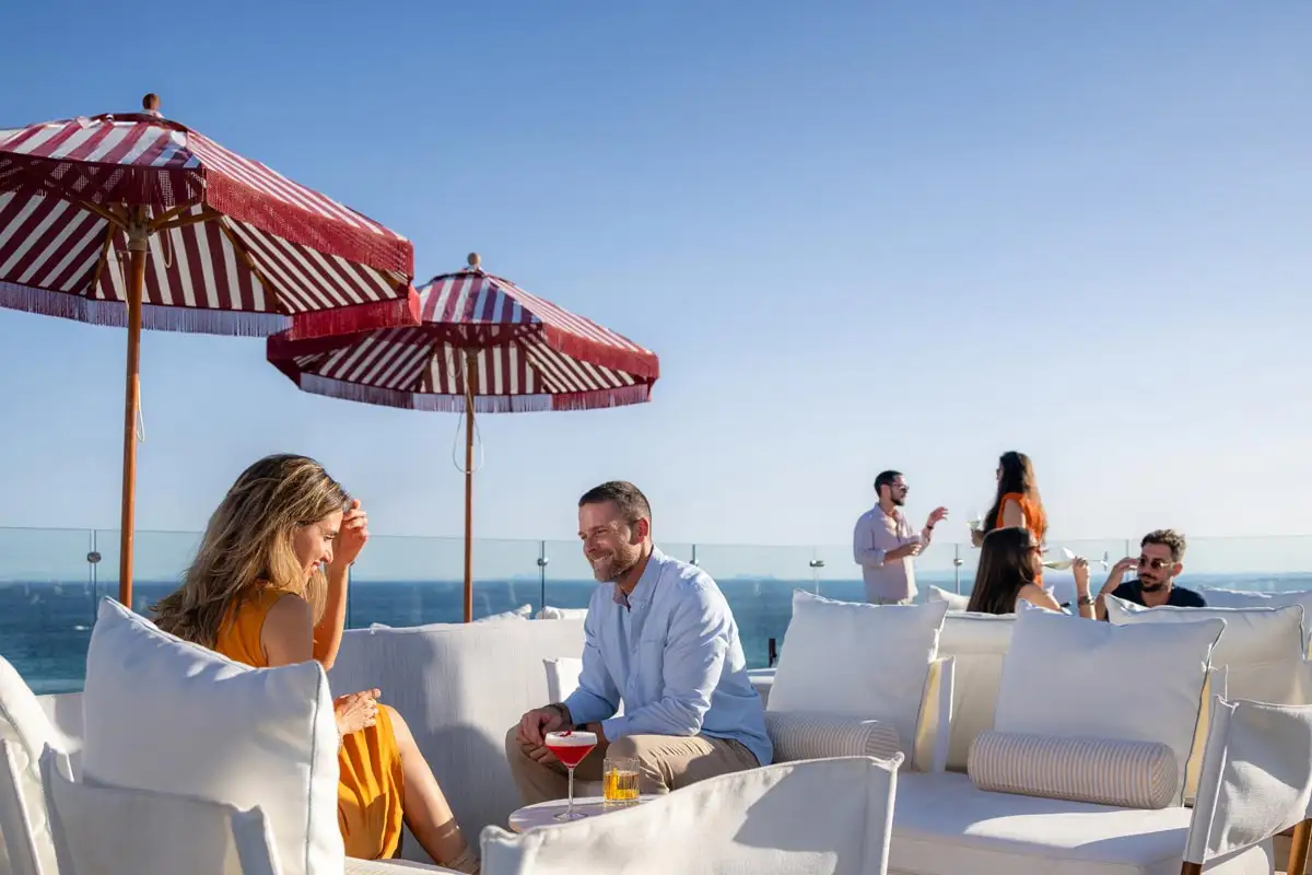 Guests relaxing with drinks under parasols at Edge at El Fuerte terrace in Marbella