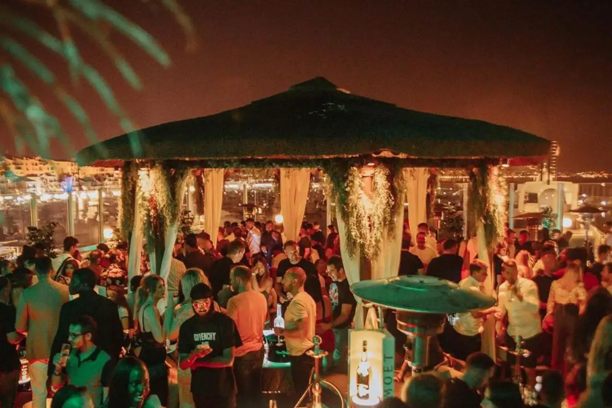 Crowd partying under canopies at night at Pangea rooftop in Marbella
