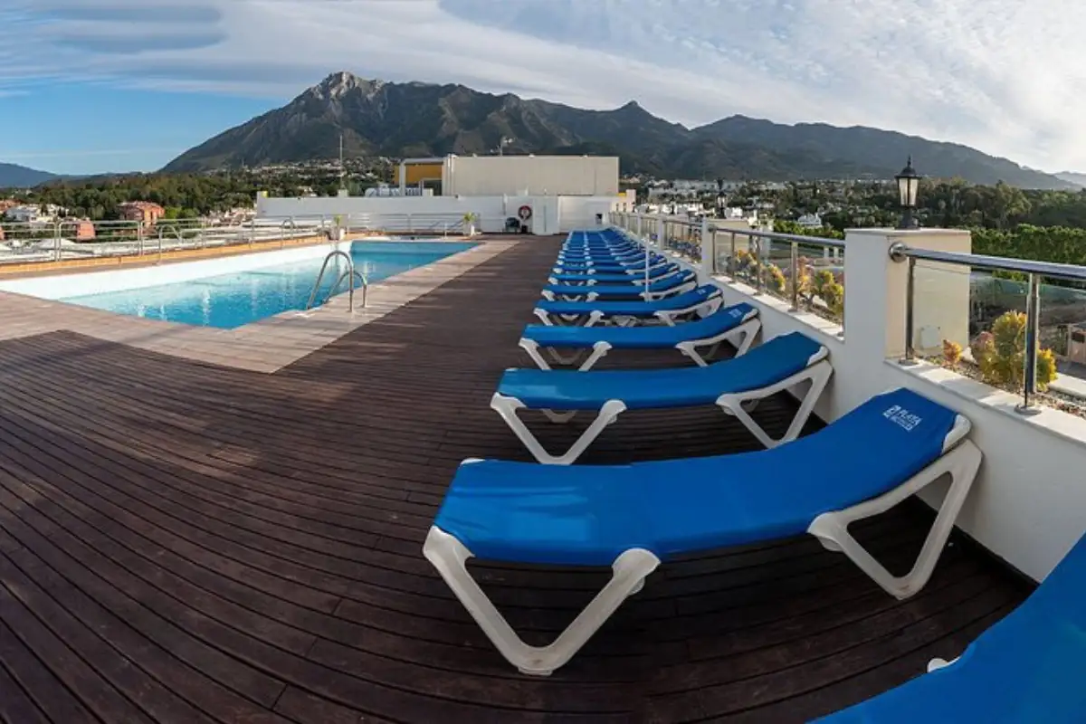 Blue loungers beside the rooftop pool with mountain backdrop at Senator Hotel, Marbella