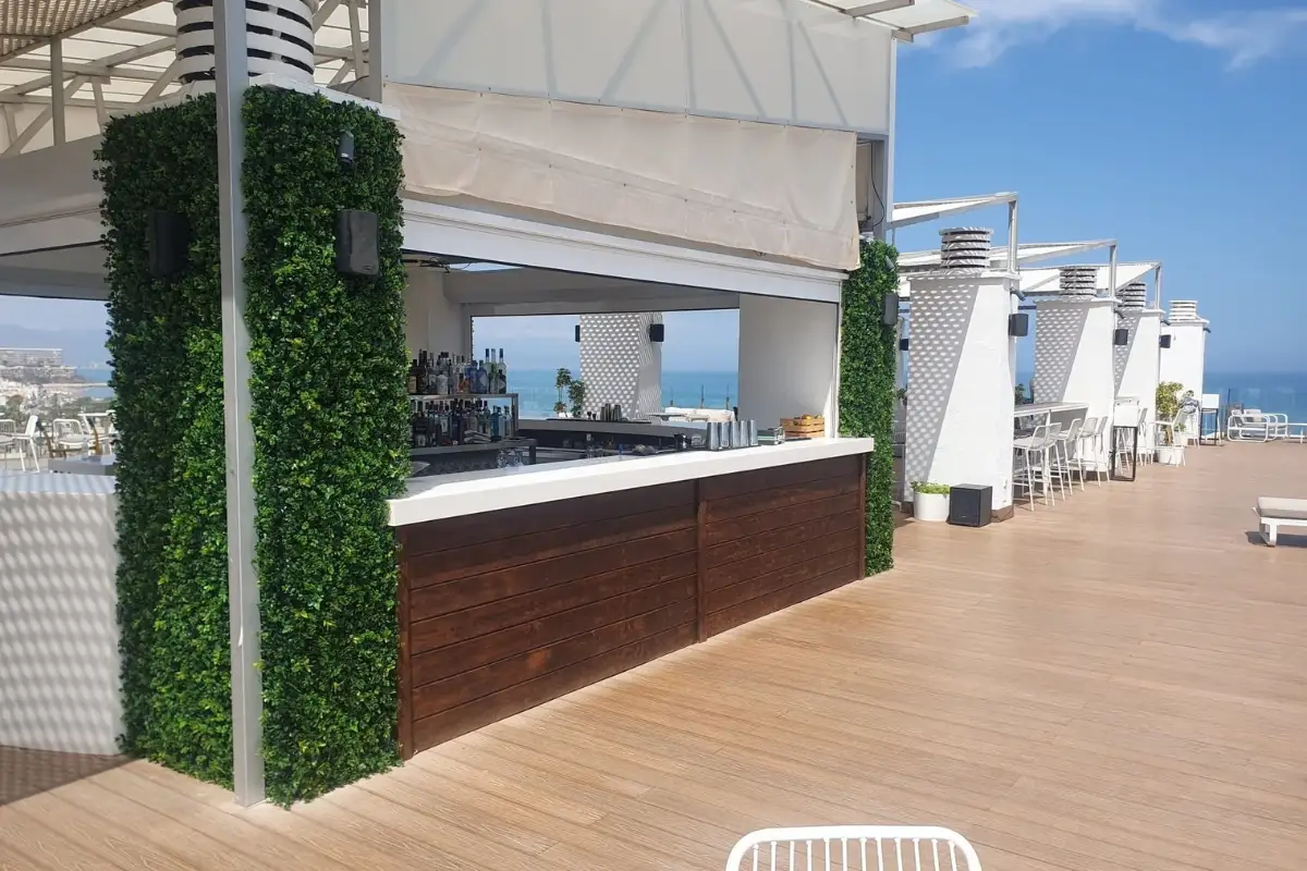 Decked bar counter framed by greenery at Barracuda rooftop in Torremolinos